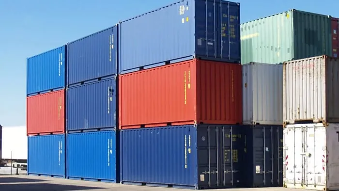 Contenedores marítimos de colores apilados en un depósito, entre ellos unidades reefer para carga refrigerada